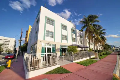 a white building with palm trees in front of it at Venezia Hotel By At Mine Hospitality in Miami Beach