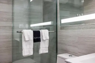a bathroom with a glass shower door and towels at Venezia Hotel By At Mine Hospitality in Miami Beach