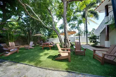 a yard with chairs and tables and a tree at The Leeward Apartments By Lowkl in Fort Lauderdale