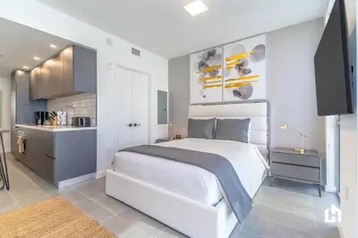 a bedroom with a large white bed and a kitchen at Downtown Miami Condos by Lua Host in Miami