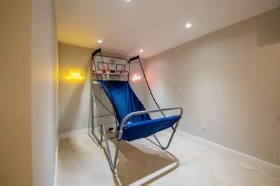 a batting cage in a room with a blue chair at Super Fun Villa Game Room BY THE GLAMHOMES in North Miami Beach