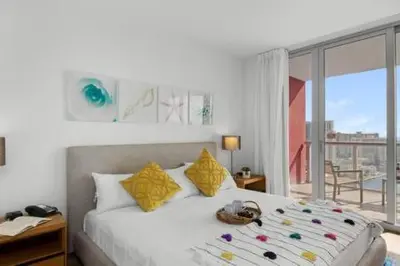 a bedroom with a bed with yellow pillows and a window at Apartment w Balcony Gym Near Beach in Hallandale Beach