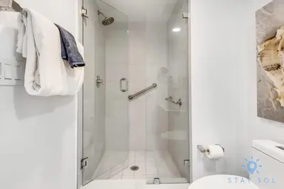 a white bathroom with a shower and a toilet at Apartment w Balcony Gym Near Beach in Hallandale Beach