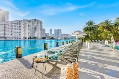 a row of chairs and tables next to a swimming pool at Apartment w Balcony Gym Near Beach in Hallandale Beach