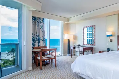 a hotel room with a bed and a desk and a window at TRUMP INTERNATIONAL BEACH RESORT 2 BEDROOM APARTMENT 1600 Sf Ocean and Bay View in Miami Beach