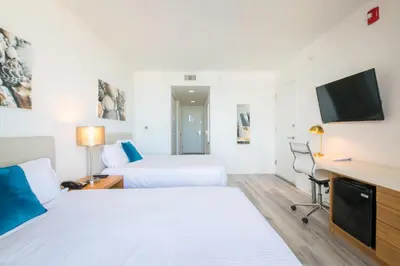 a hotel room with two beds and a flat screen tv at Infinite View Balcony & Pool Gym Near Beach in Hallandale Beach