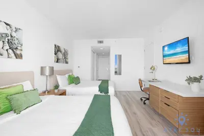 a bedroom with two beds and a desk in it at Infinite View with Balcony and Resort, Pool, Gym in Hallandale Beach