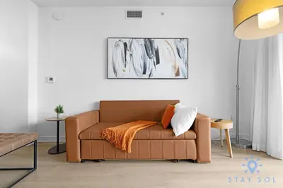 a living room with a brown couch with an orange blanket at MODERNResortBALCONY in Hallandale Beach
