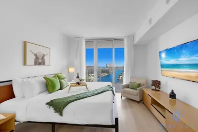 a white bedroom with a large bed and a desk at Infinite View Balcony Pool in Hallandale Beach