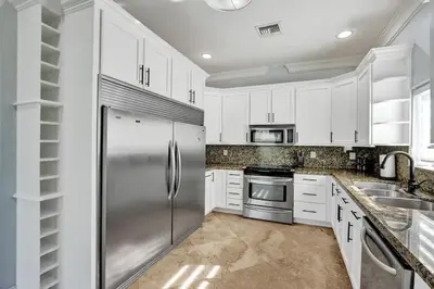 a kitchen with white cabinets and a stainless steel refrigerator at Hot Tub! Roof Top! Firepit! Boat Dock! in Fort Lauderdale