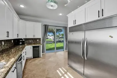 a kitchen with white cabinets and a stainless steel refrigerator at Hot Tub! Roof Top! Firepit! Boat Dock! in Fort Lauderdale
