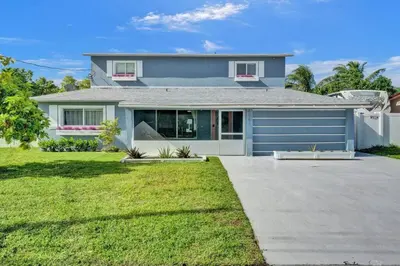 a house with a blue garage in a yard at Hot Tub! Roof Top! Firepit! Boat Dock! in Fort Lauderdale