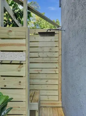 a wooden fence with a wooden bench next to a wall at Hot Tub! Roof Top! Firepit! Boat Dock! in Fort Lauderdale