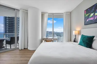 a bedroom with a large bed and large windows at Ocean Views Perfect Location Resort Amenities in Hallandale Beach