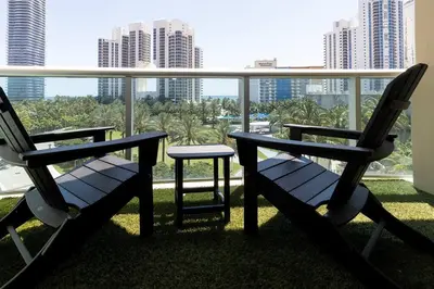 two chairs and a table on a balcony with buildings at Modern Oceanview Condo - Steps to the Beach! in Miami Beach