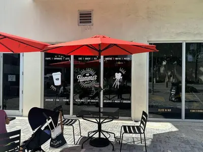 a table and chairs under an umbrella in front of a store at Modern Oceanview Condo - Steps to the Beach! in Miami Beach
