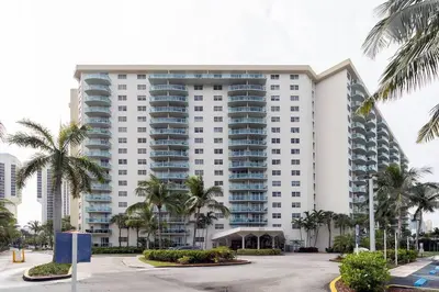 a large building with palm trees in front of it at Modern Oceanview Condo - Steps to the Beach! in Miami Beach
