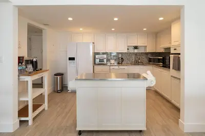 a kitchen with white cabinets and a white refrigerator at Stunning & Spacious Resort-Style Condo Across From Beach! in Miami Beach