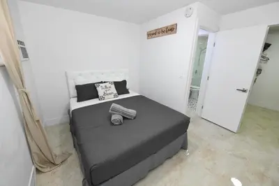 a bedroom with a large bed in a white room at 4-PLEX in Fort Lauderdale
