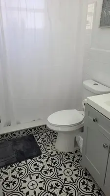 a bathroom with a toilet and a black and white tile floor at Funston in Hollywood