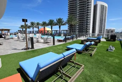 a group of blue lounge chairs on the grass near a pool at Lyfe-1005 in Hollywood
