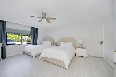 two beds in a white bedroom with a ceiling fan at Deco Boutique Hotel in Fort Lauderdale