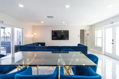 a living room with a glass table and blue chairs at Hollywood Paradise Luxury 4BR 3BA Home and Outdoor Fun with Heated Pool in Hollywood