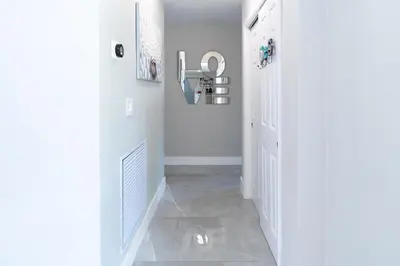 a hallway with a white door and a tile floor at Hollywood Paradise Luxury 4BR 3BA Home and Outdoor Fun with Heated Pool in Hollywood