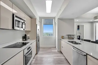 a kitchen with white counters and a large window at Luxury condo with ocean view 4Bedrooms 3Bathrooms in Hallandale Beach