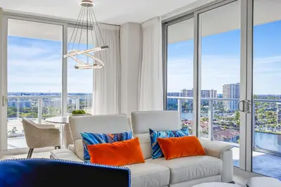 a living room with a white couch and orange pillows at Hyde Beach House - Stunning 2bd 2ba - Apt - Ocean & Intercostal views in Hollywood