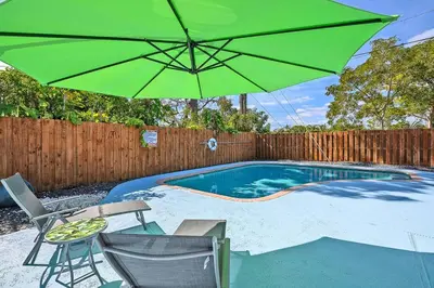 a green umbrella sitting next to a swimming pool at Enjoy and relax around Fort Lauderdale area!! in Fort Lauderdale