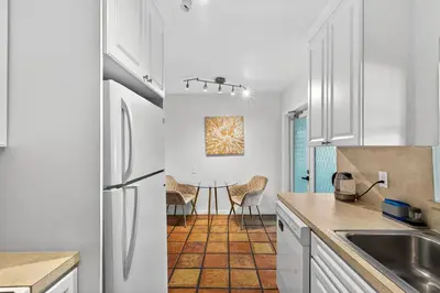 a kitchen with a refrigerator and a table with chairs at Sunny 2-Bedroom Miami Retreat with a Bright, Spacious Living Area & Relaxing Outdoor Seating in Fort Lauderdale