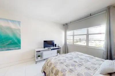 a bedroom with a bed and a tv and a window at Decoplage Paradise - Main Home in Miami Beach