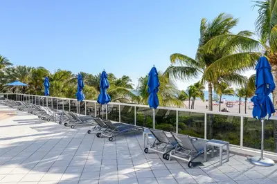 a row of beach chairs with blue umbrellas at Decoplage Paradise - Main Home in Miami Beach