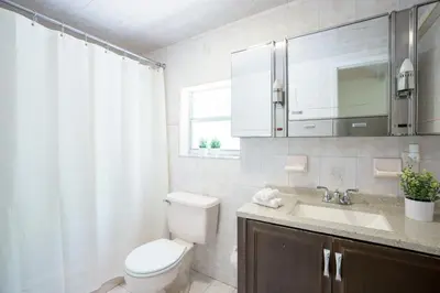 a bathroom with a toilet and a sink and a window at Modern 3-Bedroom in the Heart of Wynwood Art District in Miami