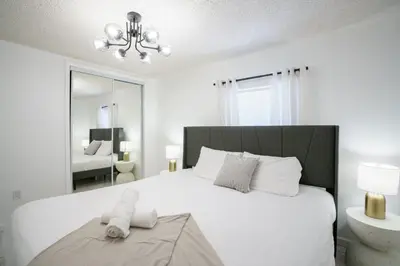 a white bedroom with a large bed and a mirror at Modern 3-Bedroom in the Heart of Wynwood Art District in Miami