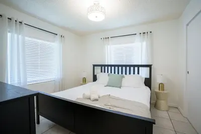 a bedroom with a large bed with white walls and windows at Modern 2 Bedroom in the Heart of Wynwood Art District in Miami