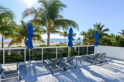 a patio with chairs and blue umbrellas and the beach at Decoplage Paradise - Unit A in Miami Beach