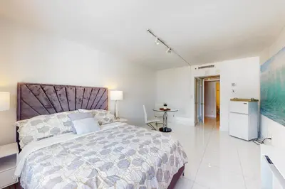 a bedroom with a large bed and a kitchen at Decoplage Paradise - Unit A in Miami Beach