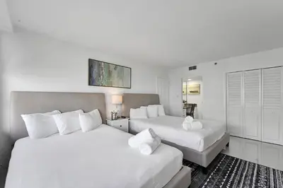 two beds in a hotel room with white walls at Cozy Beachfront 2 BDR & 2 BA Miami Beach Condo in Miami Beach