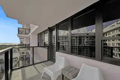 a balcony with two white chairs and large windows at Cozy Beachfront 2 BDR & 2 BA Miami Beach Condo in Miami Beach