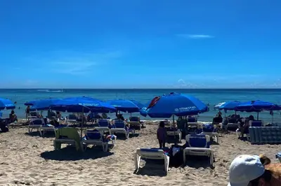a beach with chairs and blue umbrellas and the ocean at Beachfront hotel room to relax and unwind 09B in Hallandale Beach