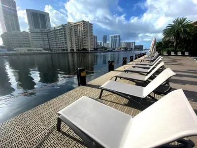 a row of white lounge chairs on a pier next to the water at Beachfront hotel room to relax and unwind 09B in Hallandale Beach