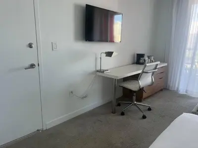 a bedroom with a desk with a chair and a television at Beachfront hotel room to relax and unwind 09B in Hallandale Beach