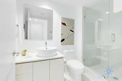 a white bathroom with a sink and a shower at Upper studio - Balcony - Pool - Gym - Near Beach in Hallandale Beach