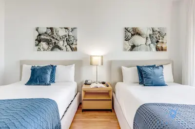 two beds with blue pillows in a room at Apartment with Balcony, Gym, Pool in Hallandale Beach