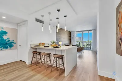 a kitchen with a island with bar stools at Pool Apartment with Balcony, Near Beach in Hallandale Beach