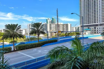 a parking lot with palm trees and buildings at Pool Apartment with Balcony, Near Beach in Hallandale Beach