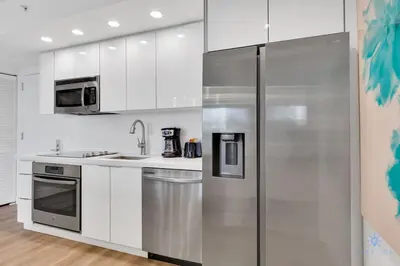 a stainless steel refrigerator in a kitchen with white cabinets at Pool Apartment with Balcony, Near Beach in Hallandale Beach