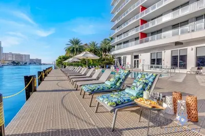 a row of chaise lounge chairs next to a building at Modern Resort with Balcony - Near Beach - Pool in Hallandale Beach